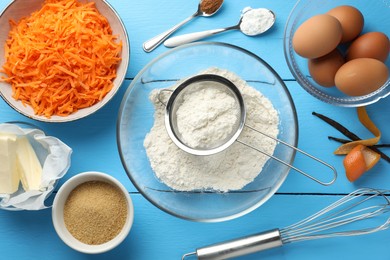 Photo of Different ingredients for making carrot cake on light blue wooden table, flat lay