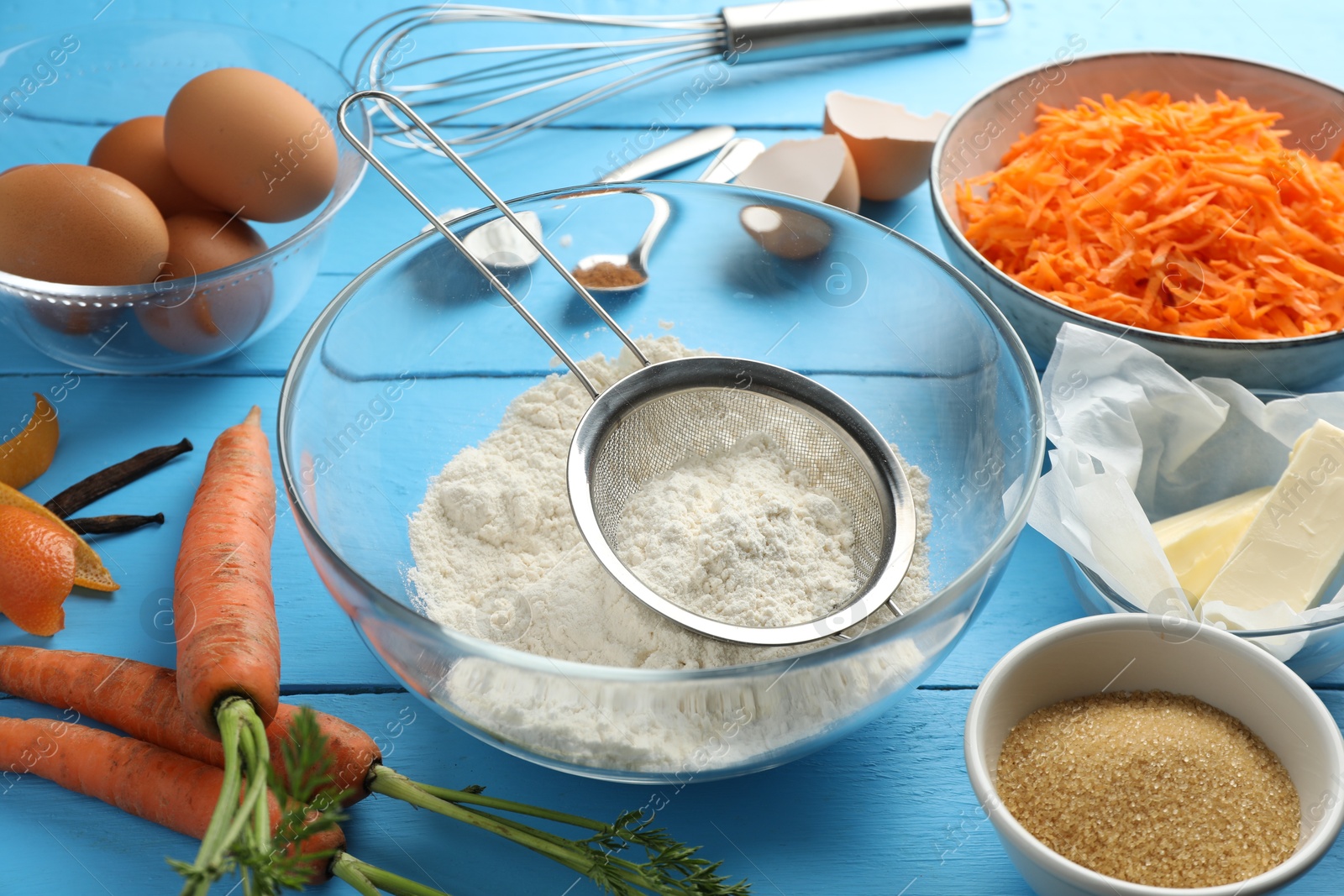 Photo of Different ingredients for making carrot cake on light blue wooden table, closeup