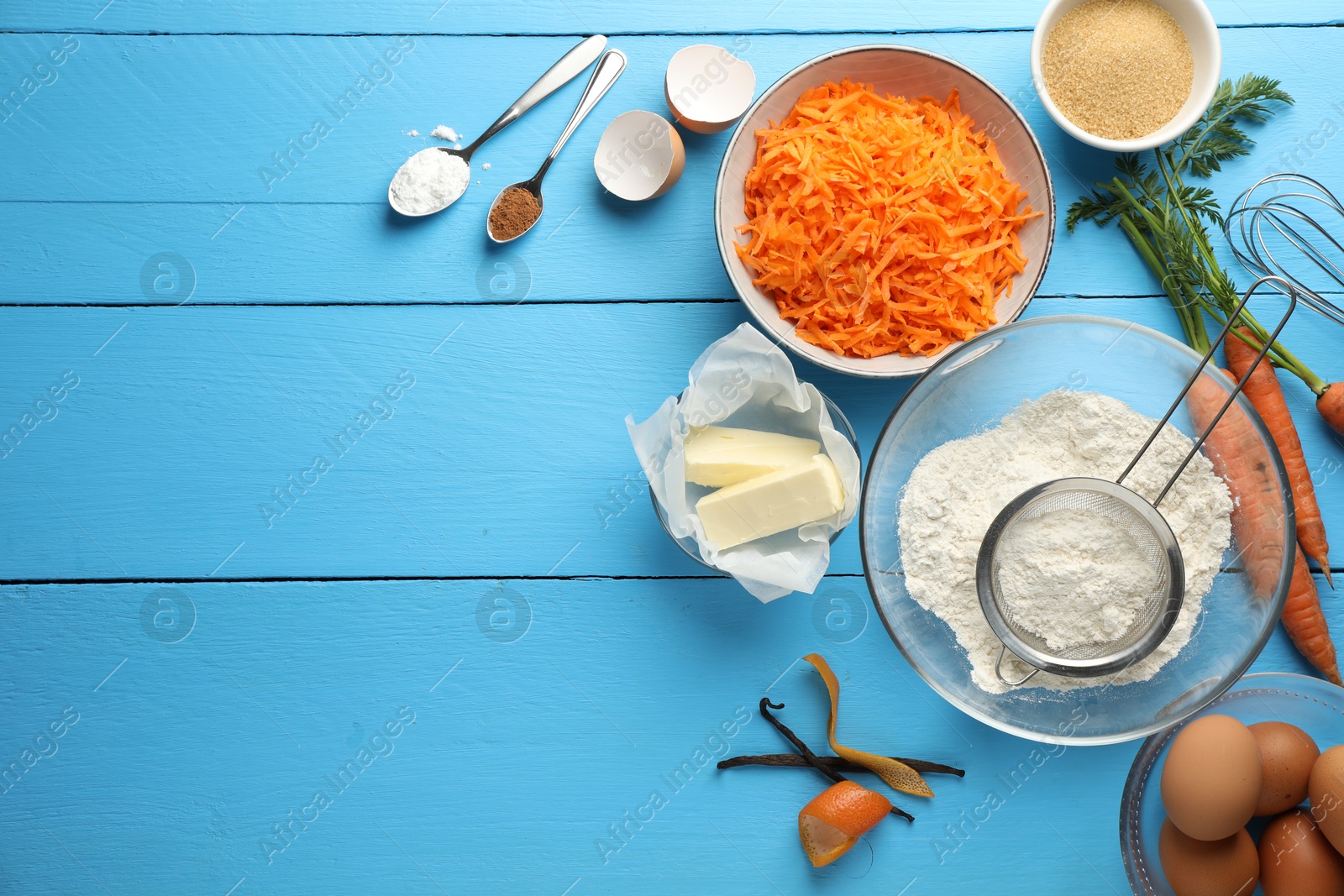 Photo of Different ingredients for making carrot cake on light blue wooden table, flat lay. Space for text