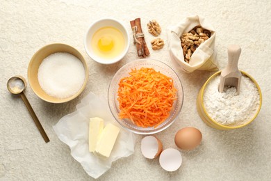 Photo of Different ingredients for making carrot cake on beige textured table, flat lay