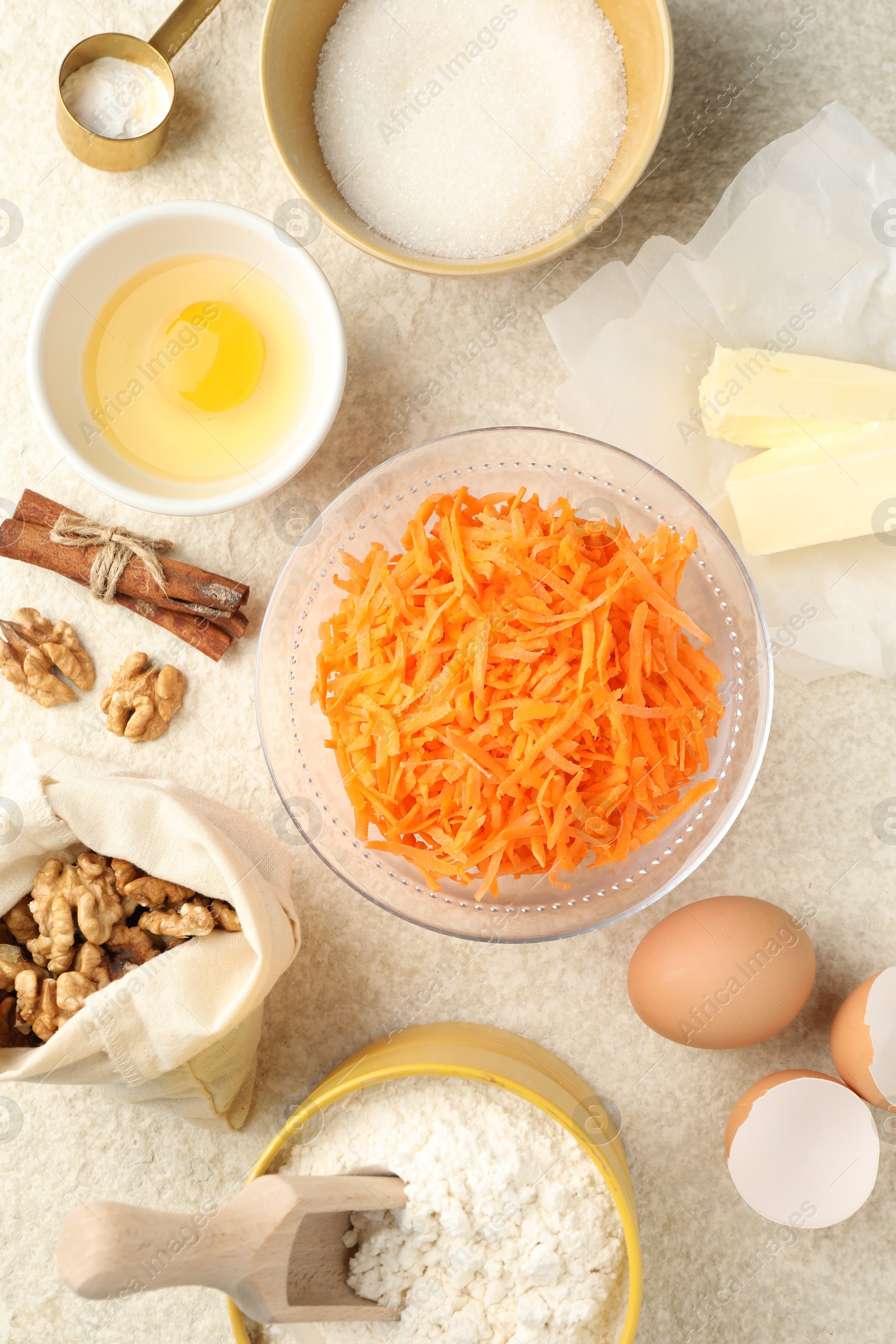 Photo of Different ingredients for making carrot cake on beige textured table, flat lay