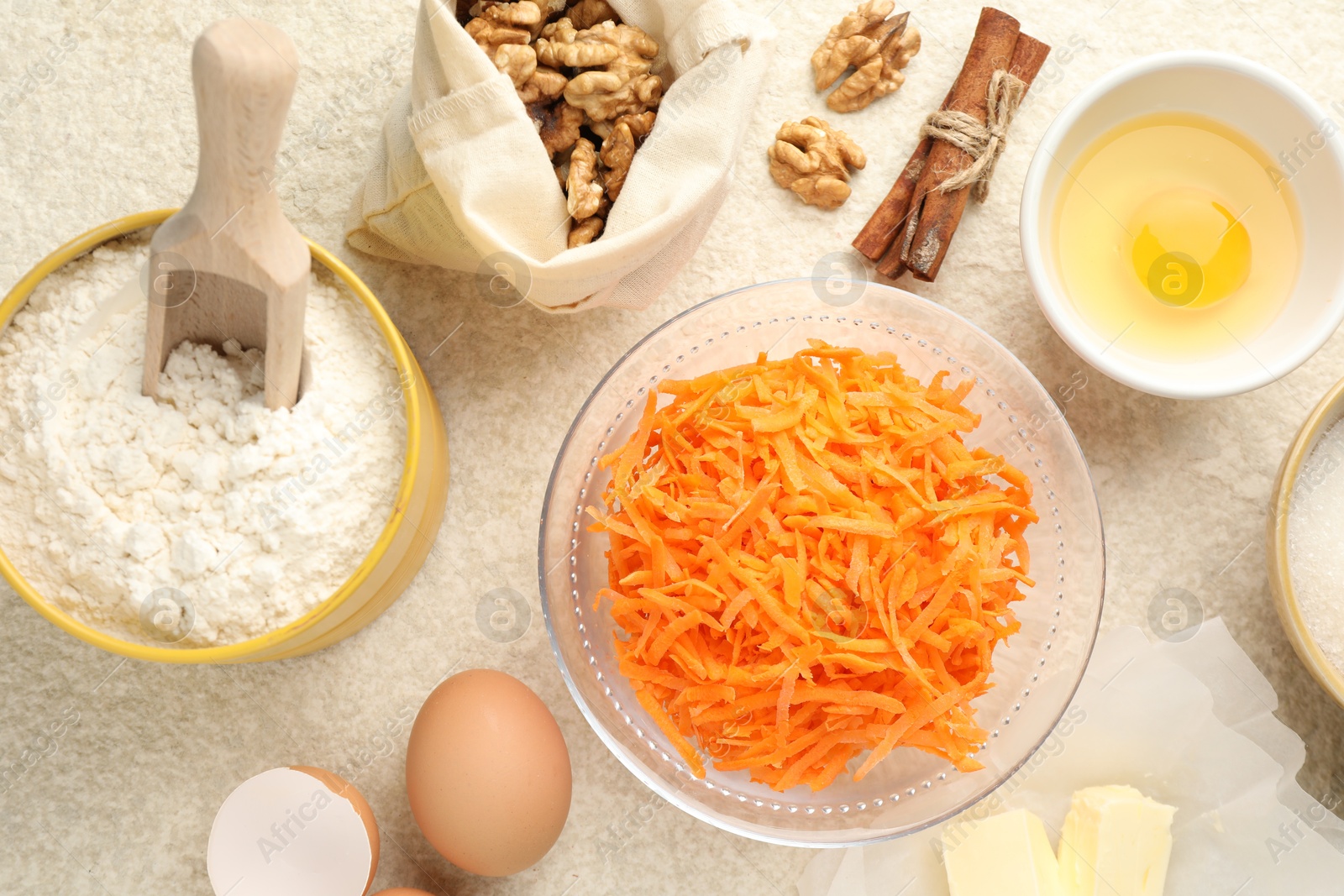 Photo of Different ingredients for making carrot cake on beige textured table, flat lay