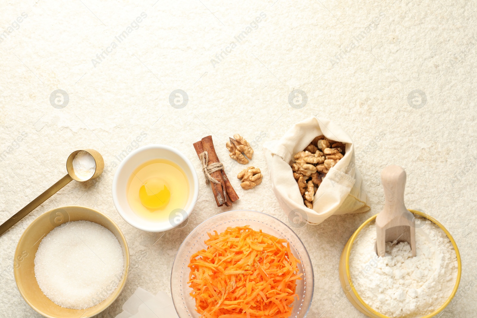 Photo of Different ingredients for making carrot cake on beige textured table, flat lay. Space for text