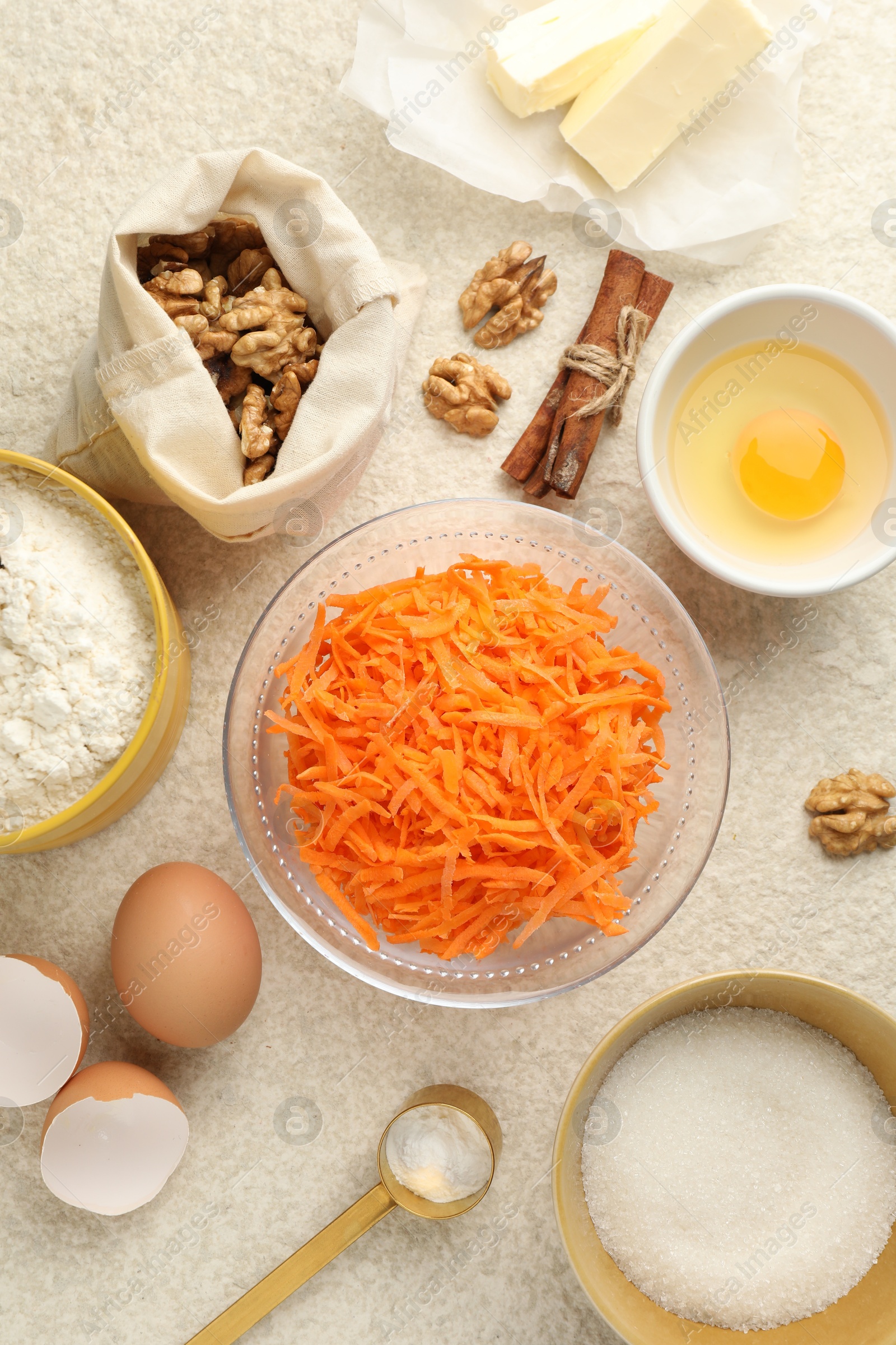 Photo of Different ingredients for making carrot cake on beige textured table, flat lay