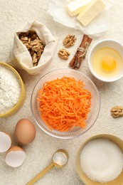 Photo of Different ingredients for making carrot cake on beige textured table, flat lay