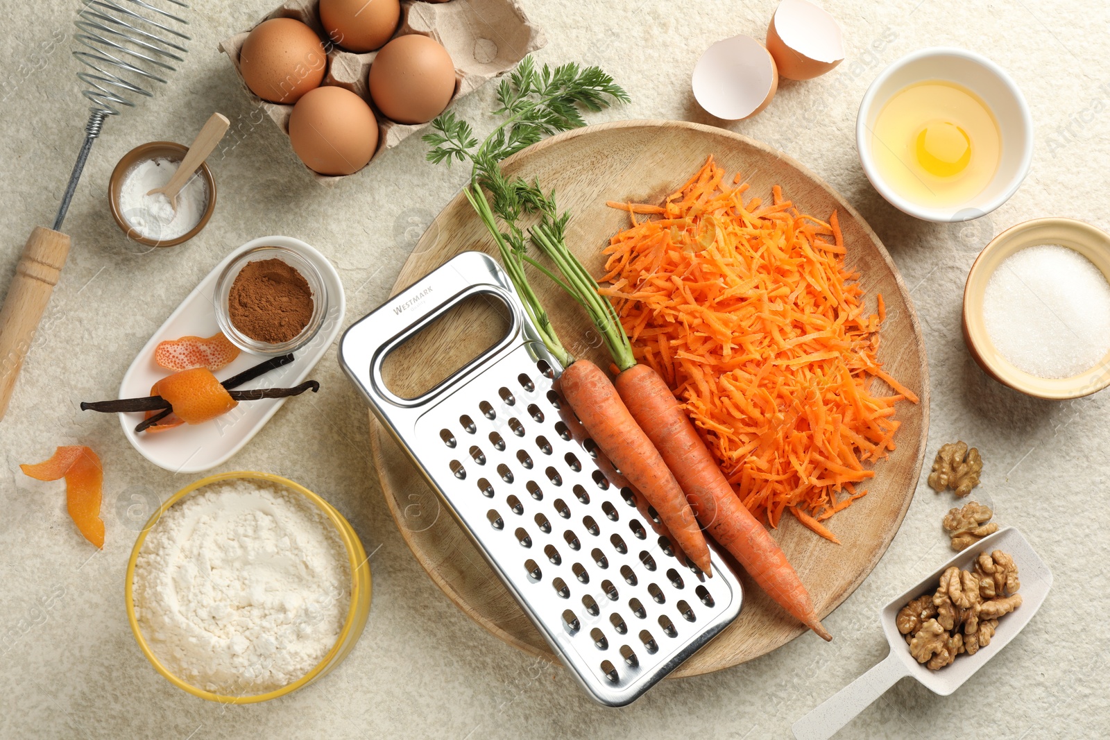 Photo of Different ingredients for making carrot cake on beige textured table, flat lay