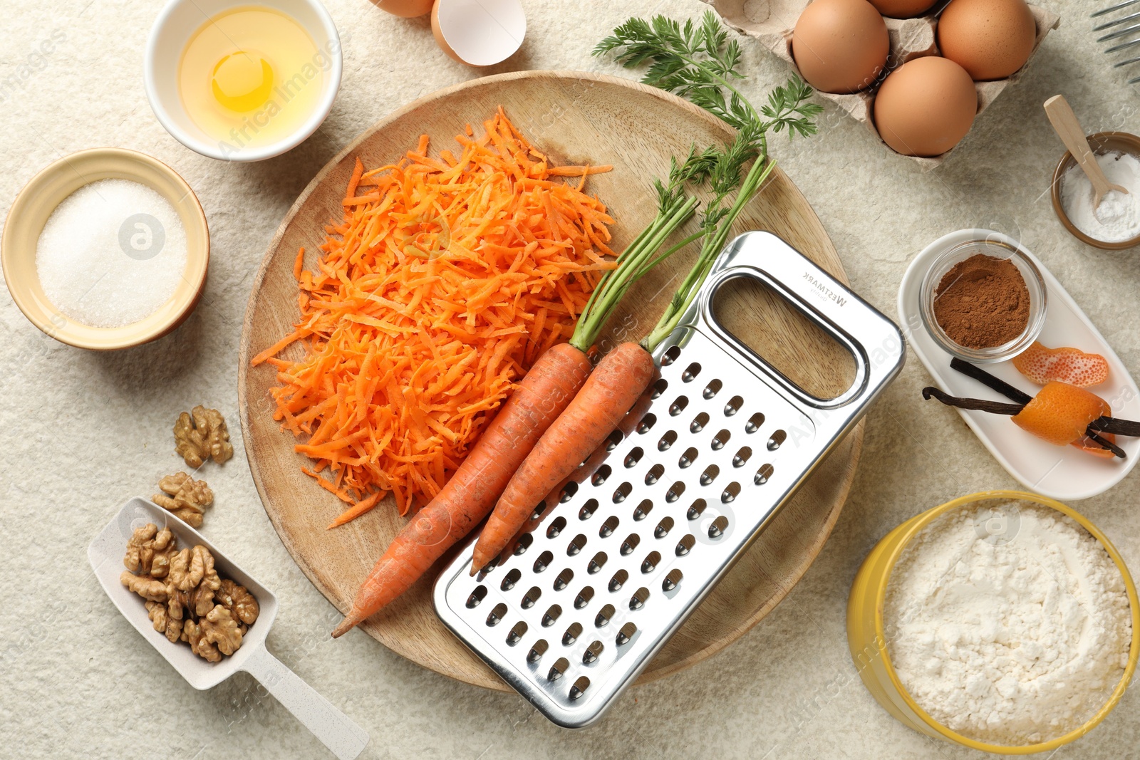 Photo of Different ingredients for making carrot cake on beige textured table, flat lay