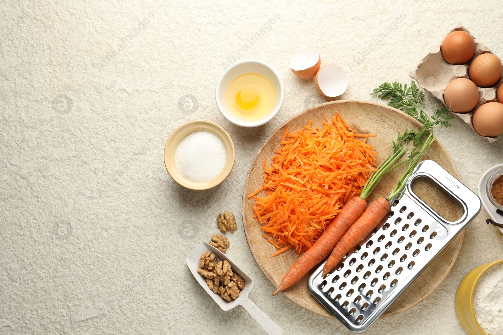 Photo of Different ingredients for making carrot cake on beige textured table, flat lay. Space for text