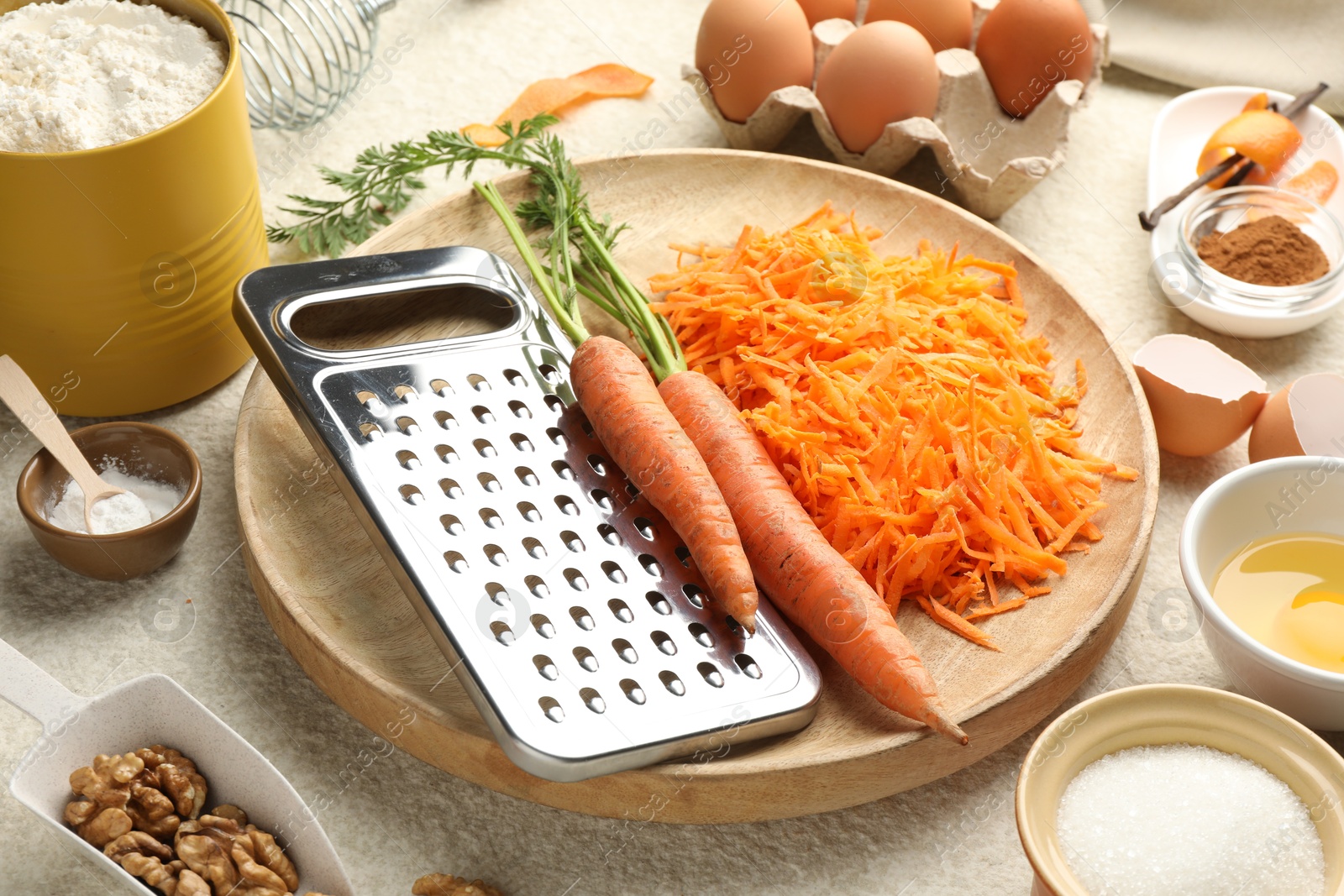 Photo of Different ingredients for making carrot cake on beige textured table, closeup