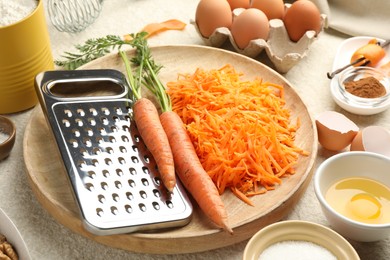 Photo of Different ingredients for making carrot cake on beige textured table, closeup