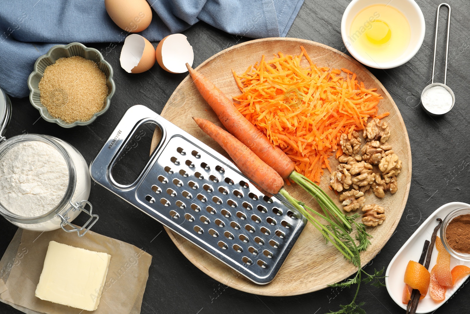 Photo of Different ingredients for making carrot cake on black table, flat lay