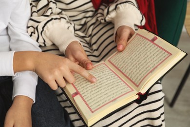 Muslim woman and her son reading Quran at home, closeup