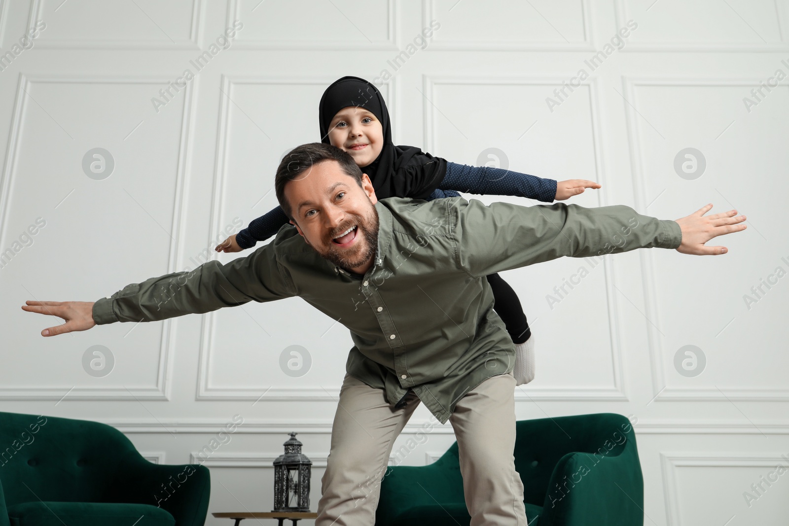 Photo of Muslim man and his daughter spending time together at home, low angle view