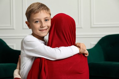 Photo of Muslim woman and her son spending time together at home