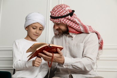 Muslim man and his son reading Quran at home