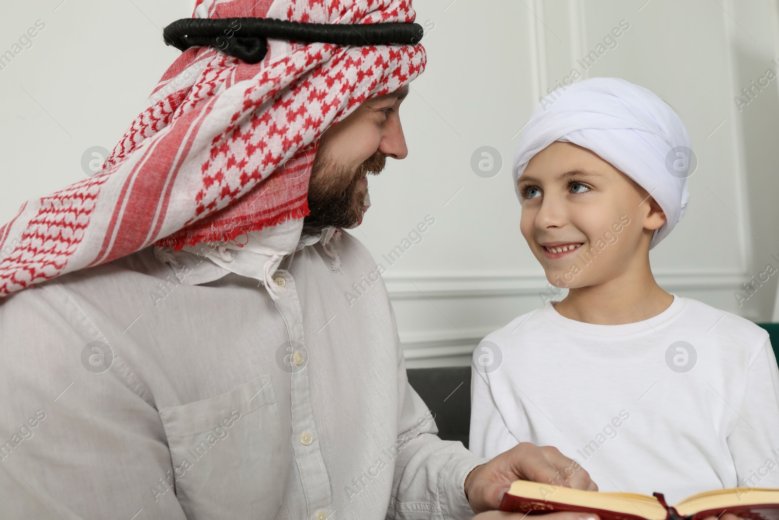 Photo of Muslim man and his son reading Quran at home