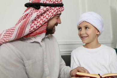 Photo of Muslim man and his son reading Quran at home