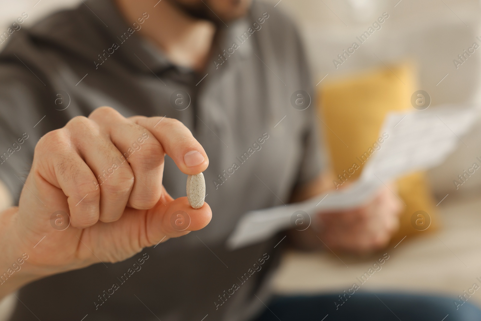 Photo of Man with pill reading instruction at home, selective focus