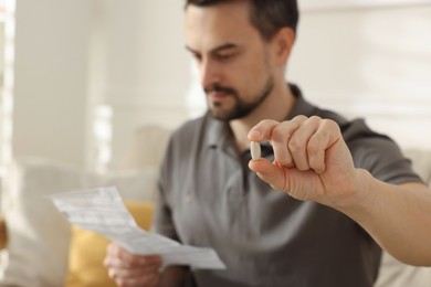 Photo of Man with pill reading instruction at home, selective focus