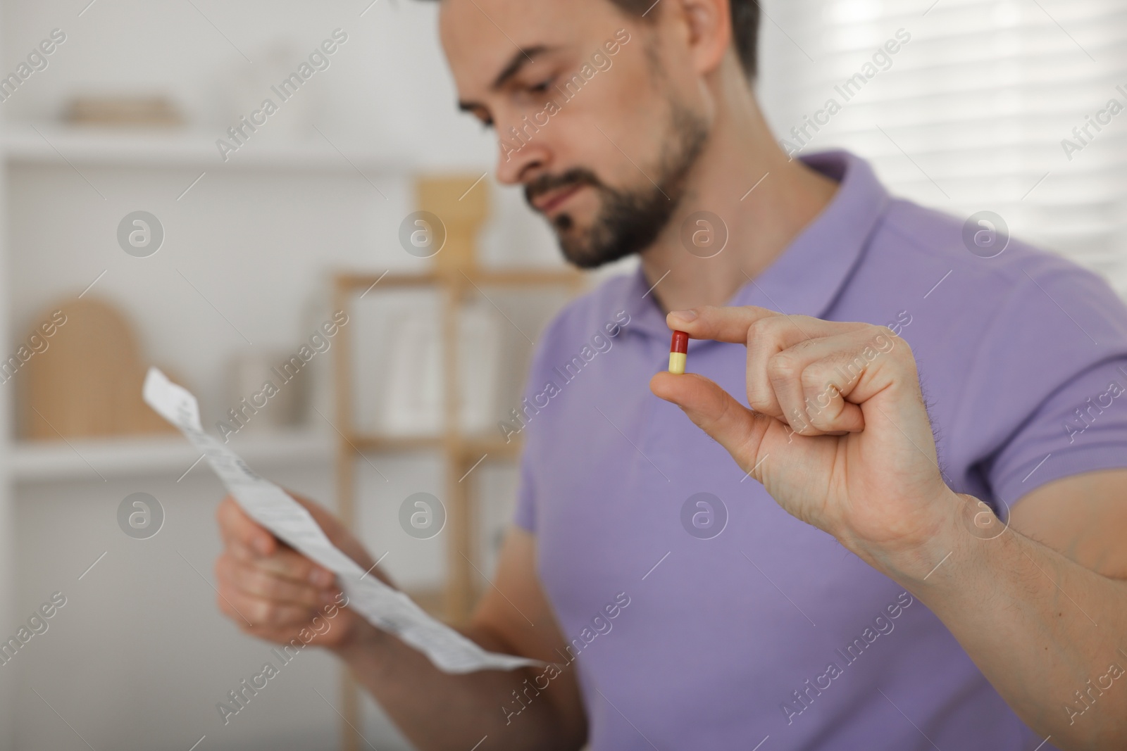 Photo of Man with pill reading instruction at home, selective focus