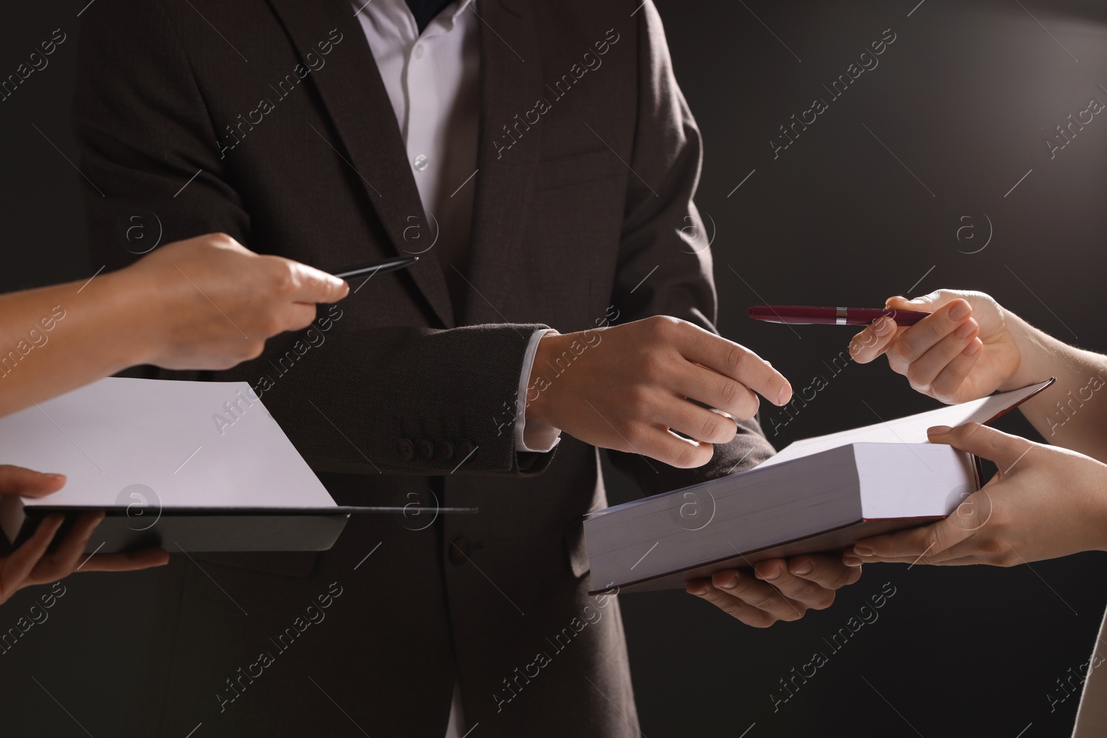 Photo of Writer signing autograph in book on black background, closeup