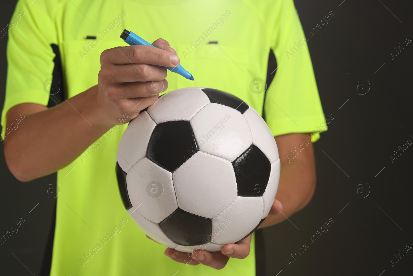 Photo of Professional player signing autograph on ball against black background, closeup