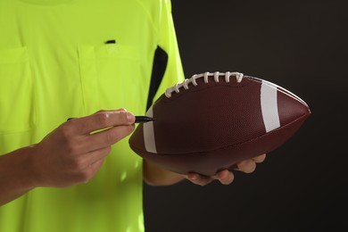 Photo of Professional player signing autograph on American football ball black background, closeup