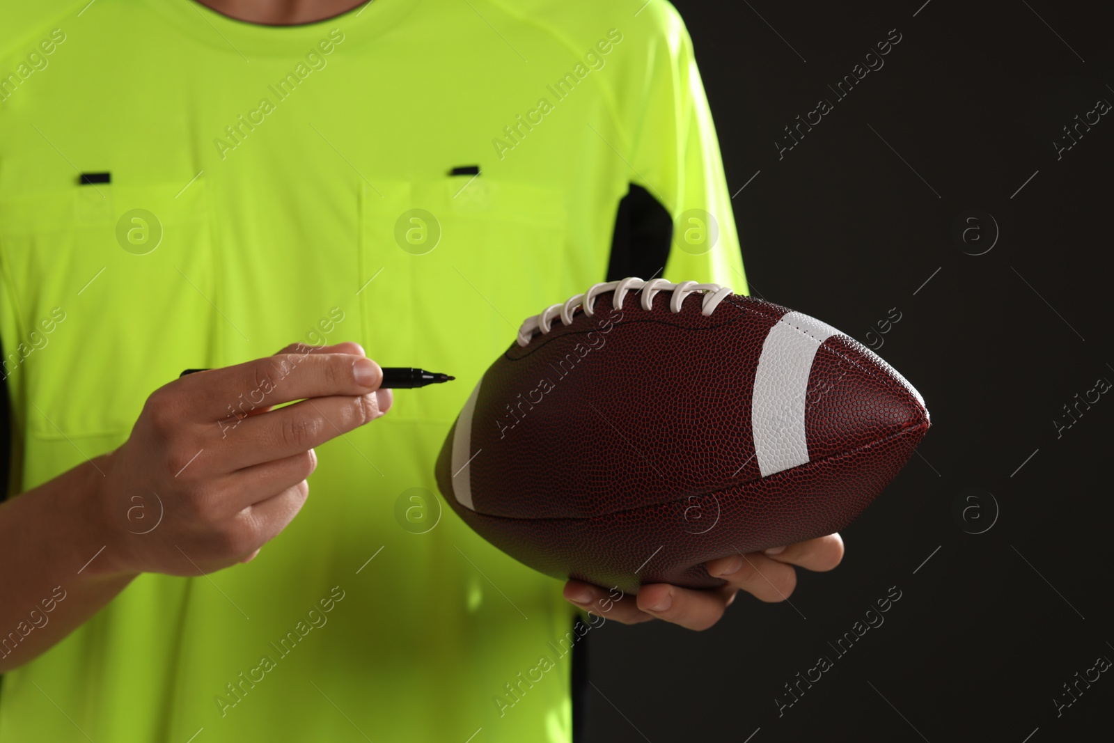 Photo of Professional player signing autograph on American football ball black background, closeup