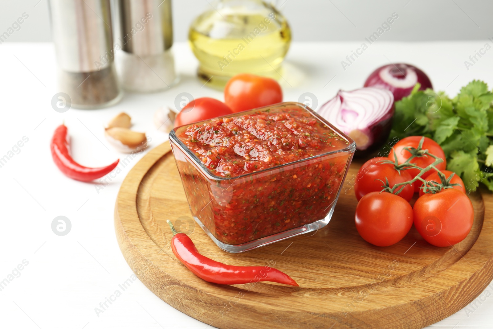 Photo of Delicious salsa sauce and ingredients on white table, closeup