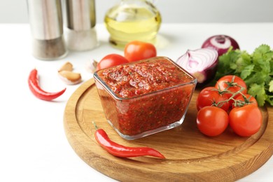 Photo of Delicious salsa sauce and ingredients on white table, closeup