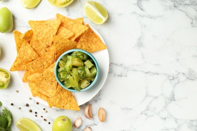 Photo of Delicious salsa with nachos on white marble table, flat lay. Space for text