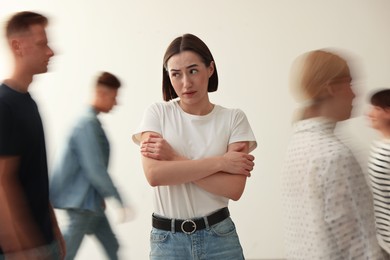 Young woman feeling uncomfortable among people indoors