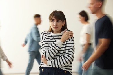 Photo of Young woman feeling uncomfortable among people indoors