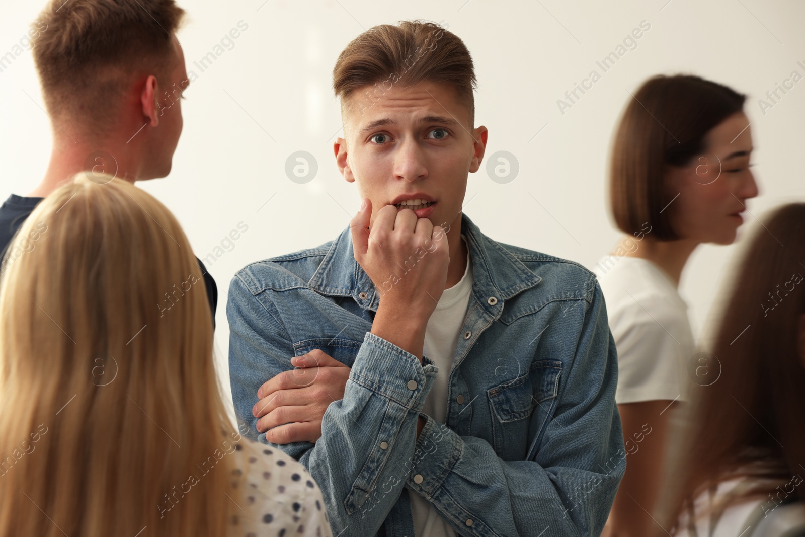 Photo of Young man feeling uncomfortable among people indoors