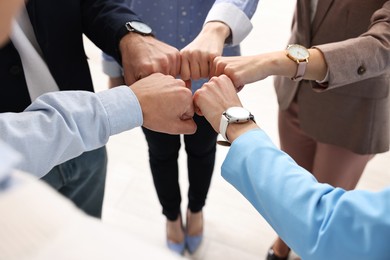 Photo of Teamwork. Group of people joining fists together indoors, closeup