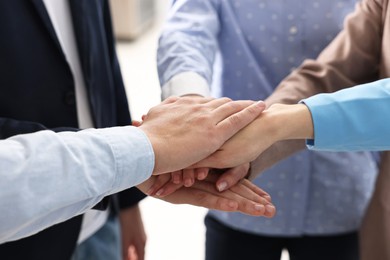 Teamwork. Group of people joining hands together indoors, closeup