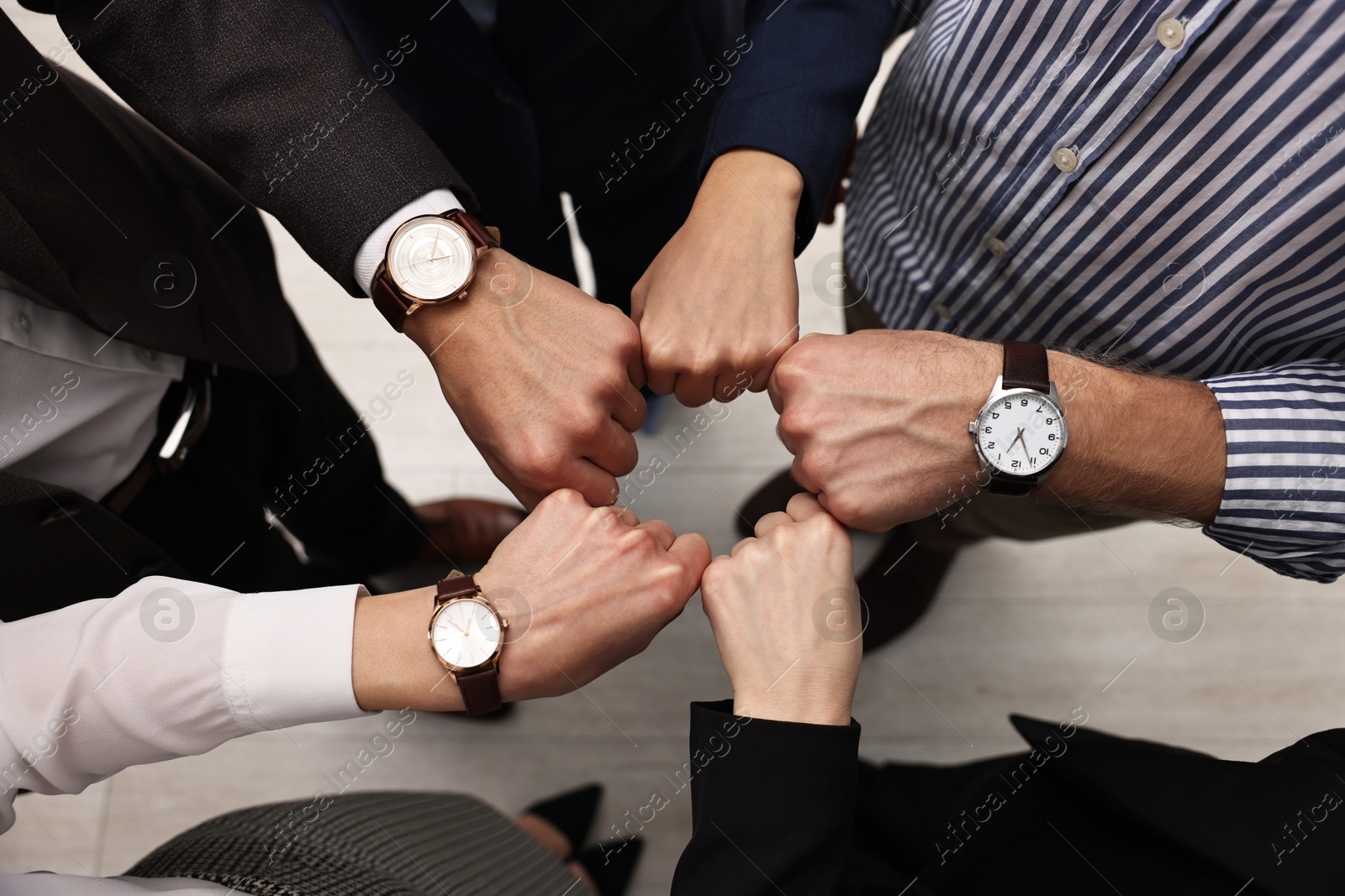 Photo of Teamwork. Group of people joining fists together indoors, top view