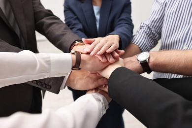 Teamwork. Group of people joining hands together indoors, closeup