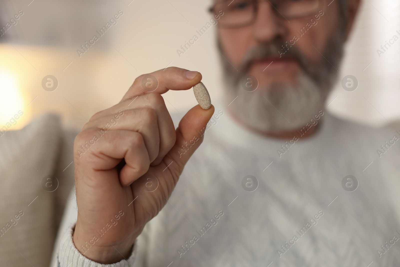 Photo of Senior man with pill at home, closeup