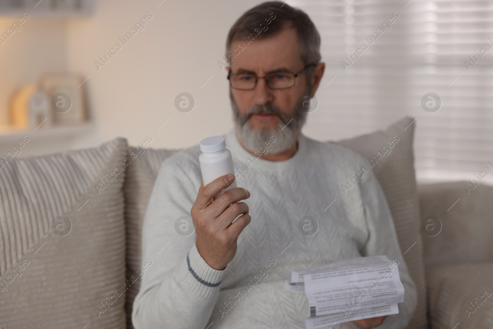 Photo of Senior man with bottle of pills and instruction at home, selective focus