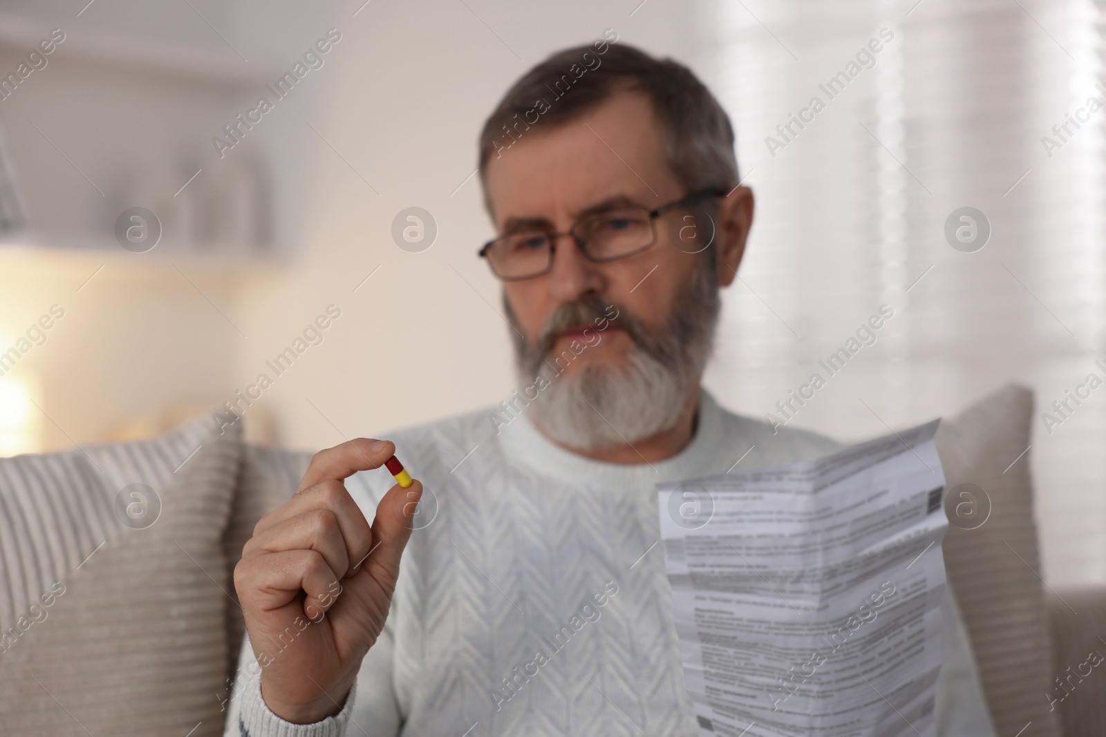 Photo of Senior man with pill and instruction at home, selective focus