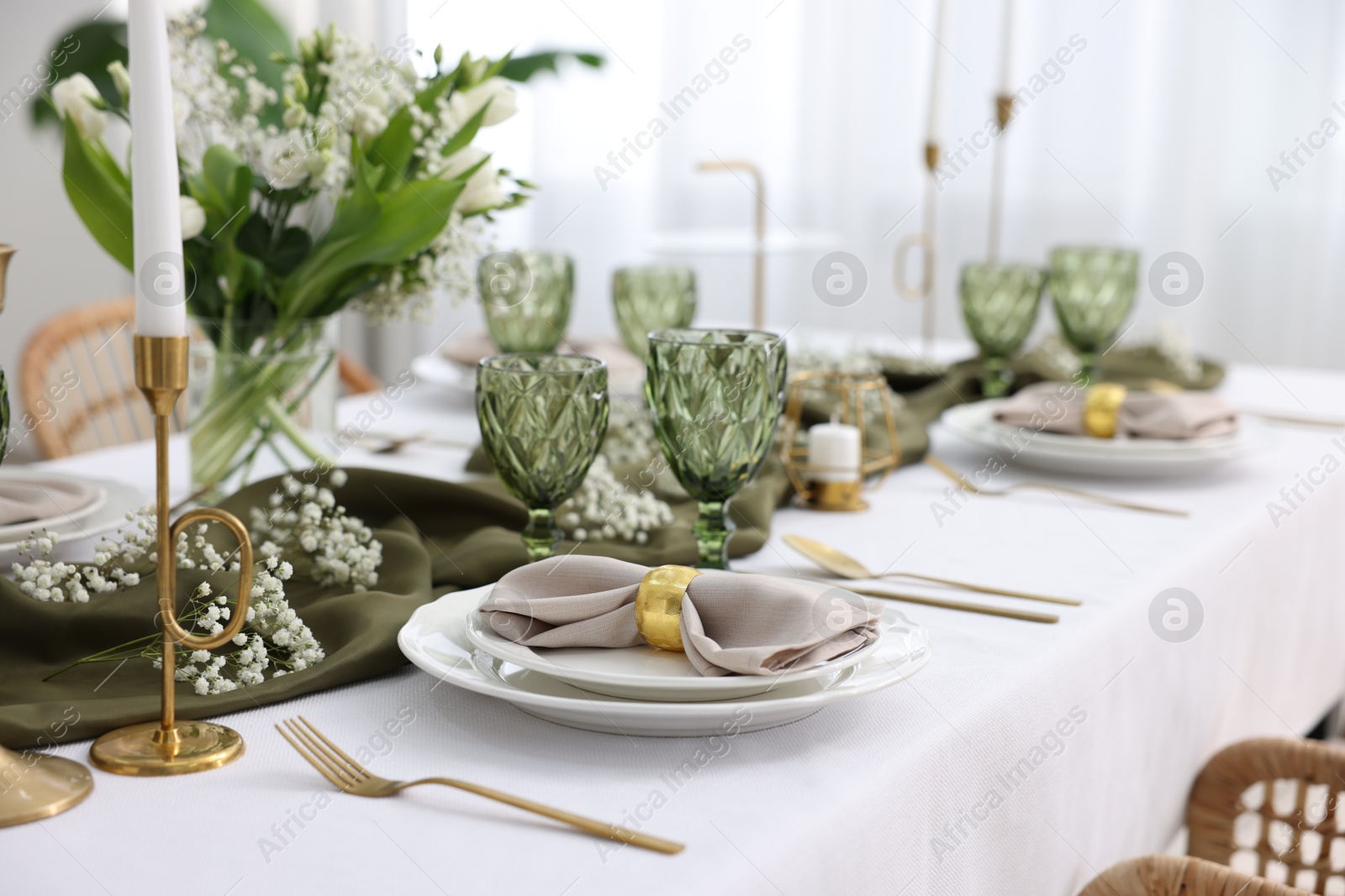 Photo of Color accent table setting with glasses, flowers and green napkins indoors, closeup