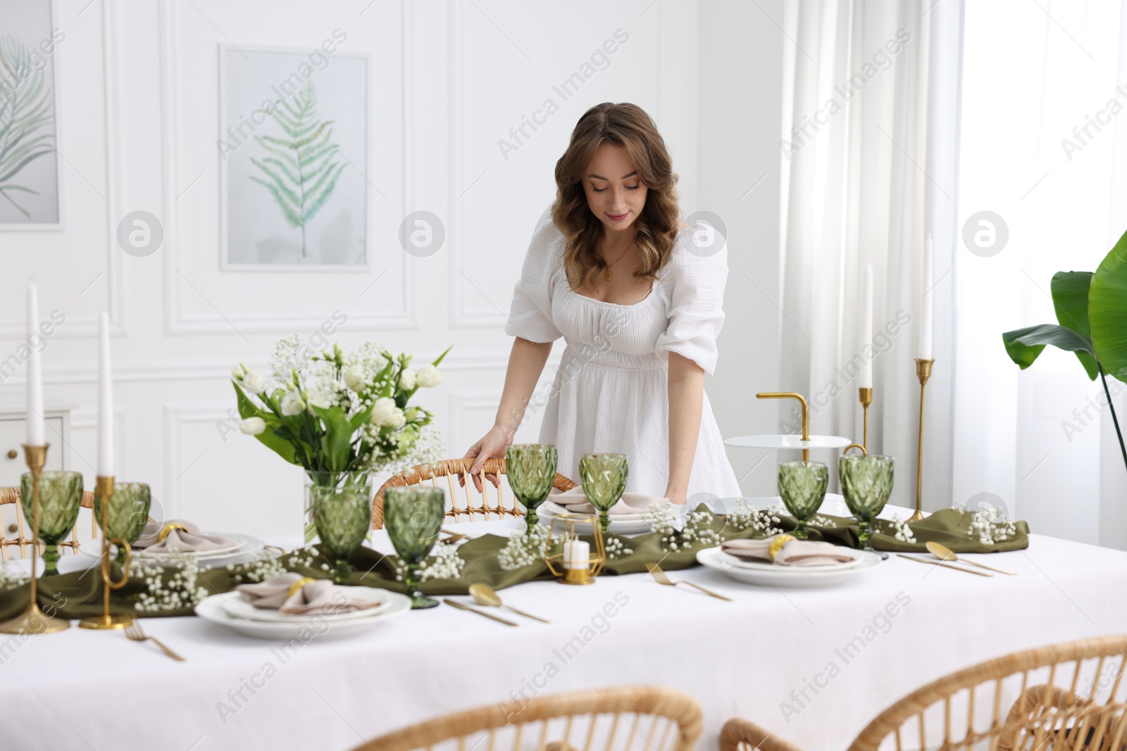 Photo of Happy young woman setting table for dinner at home