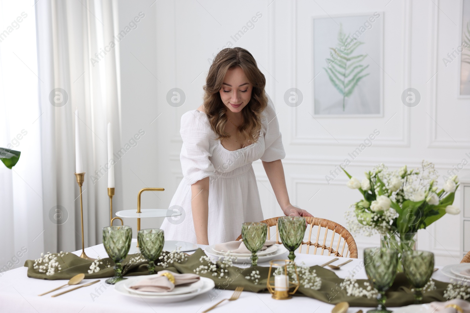 Photo of Happy young woman setting table for dinner at home