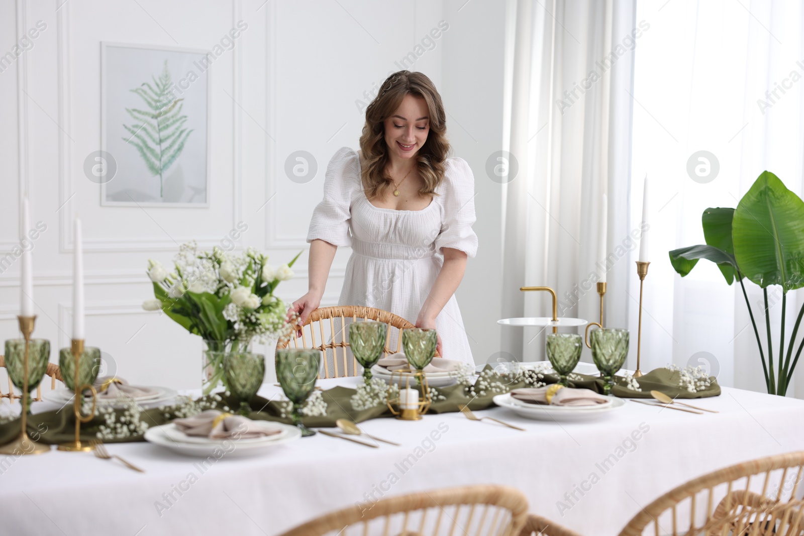 Photo of Happy young woman setting table for dinner at home