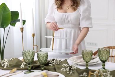 Young woman setting table for dinner at home, closeup