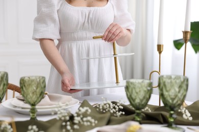 Young woman setting table for dinner at home, closeup