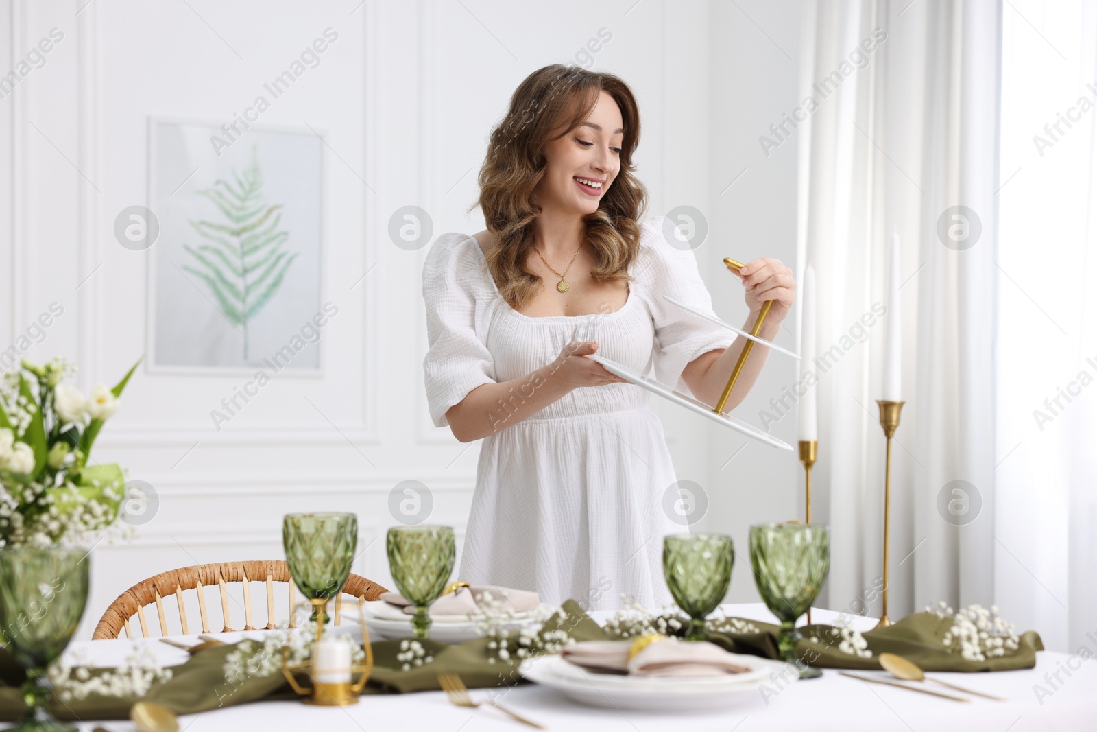 Photo of Happy young woman setting table for dinner at home