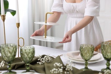 Young woman setting table for dinner at home, closeup