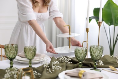 Photo of Young woman setting table for dinner at home, closeup